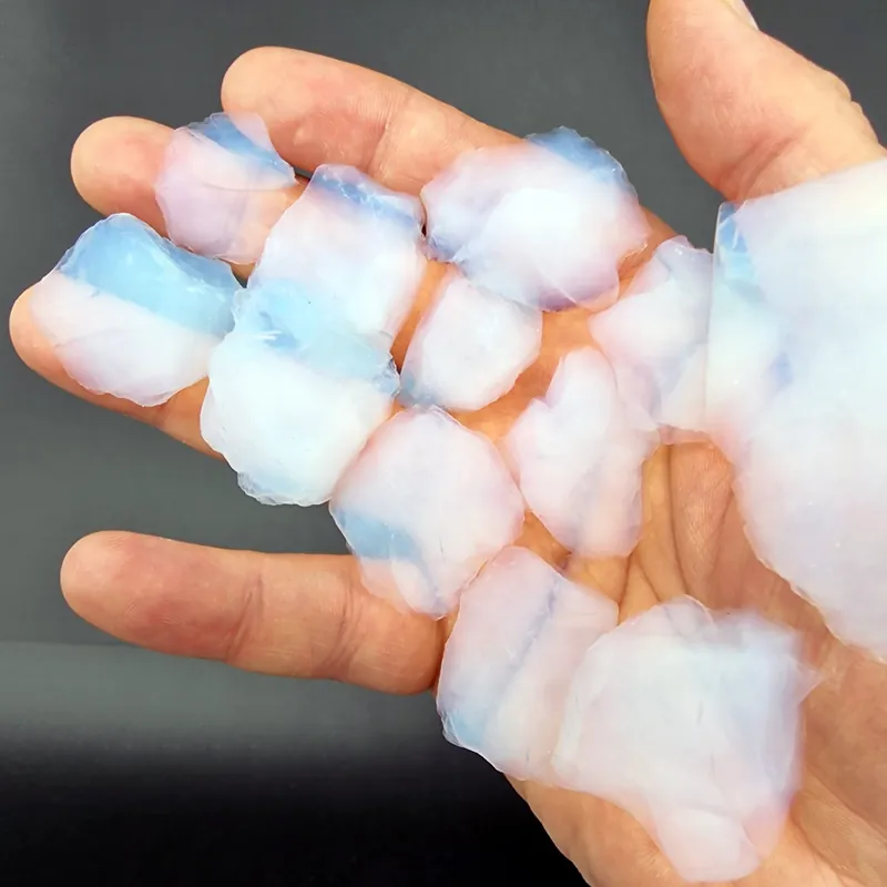 Morceaux d’aérogel de silice translucides aux reflets bleus posés dans une main
